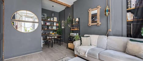 Una sala de estar moderna con un sofá gris, una mesa de comedor y una estantería.