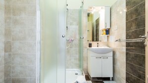 A bathroom with a glass-enclosed shower, a white sink, and a mirror above the sink. - Charming and Historic Old Town Apartments - Studio Apartment (Zadar)