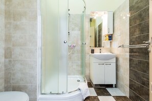 A bathroom with a glass-enclosed shower, a white sink, and a mirror above the sink. - Charming and Historic Old Town Apartments - Studio Apartment (Zadar)