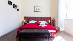 A neatly arranged bedroom with a large bed, bedside tables, a bench, and a window with curtains. - Charming and Historic Old Town Apartments - Studio Apartment (Zadar)