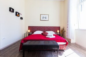 A neatly arranged bedroom with a large bed, bedside tables, a bench, and a window with curtains. - Charming and Historic Old Town Apartments - Studio Apartment (Zadar)