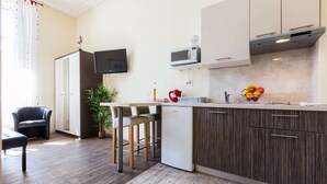 A modern kitchen with a built-in microwave, a small refrigerator, and a bar area with stools. - Charming and Historic Old Town Apartments - Studio Apartment (Zadar)