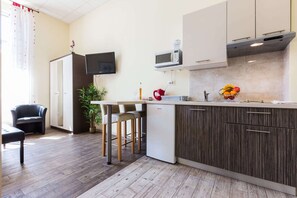 A modern kitchen with a built-in microwave, a small refrigerator, and a bar area with stools. - Charming and Historic Old Town Apartments - Studio Apartment (Zadar)