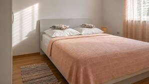 A bedroom with a bed, pillows, a bedside lamp, and a window with curtains. - 2 bedroom awesome apartment in Vir (Vir)