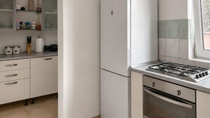 A kitchen with a white refrigerator, a gas stove, and a built-in oven. There are cabinets with handles and a countertop with various items. - 2 bedroom awesome apartment in Vir (Vir)