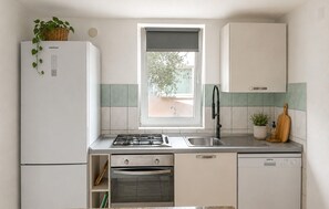 A compact kitchen with a built-in oven, a dishwasher, and a window with a view of greenery outside. - 2 bedroom awesome apartment in Vir (Vir)