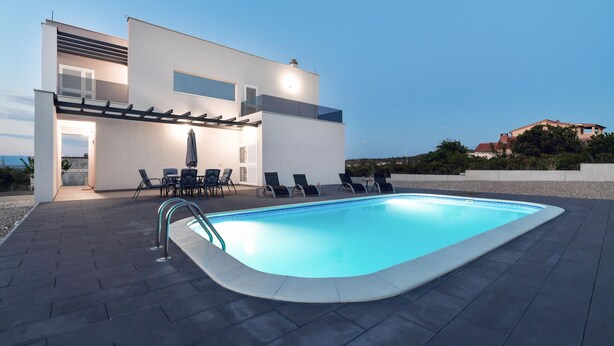 Ein moderner Poolbereich im Freien mit integriertem Pool, Liegestühlen und einer überdachten Sitzgelegenheit.