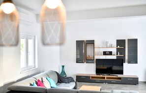 A modern living room with a grey sofa, wooden entertainment unit, and a flat-screen TV. - Awesome home in Debeljak (Debeljak)