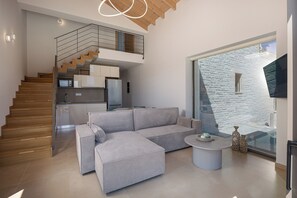 A modern living room with a sofa, a coffee table, and a staircase leading to a kitchen.