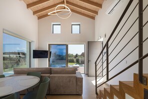 Un interior moderno con comedor, sofá, televisor y escalera.