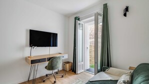 Une chambre comprenant un bureau, une chaise, un lit et un téléviseur fixé au mur.