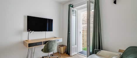 Une chambre comprenant un bureau, une chaise, un lit et un téléviseur fixé au mur.