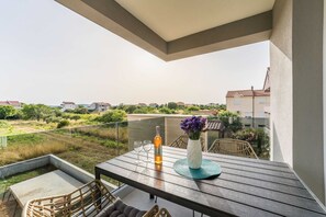 Ein Balkon mit Tisch, Stühlen, einer Weinflasche und einem Blumenstrauß.