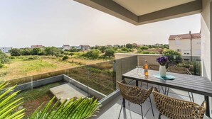 A balcony with a table, chairs, and a bottle of wine, overlooking a residential area with greenery and houses. - Luxury D Apartments - Luxury Two Bedroom Apartment With Terrace A2 (Bibinje)