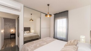 A modern bedroom with a large bed, a smaller bed, a walk-in closet, and a bathroom. - Luxury D Apartments - Luxury Two Bedroom Apartment With Terrace A2 (Bibinje)