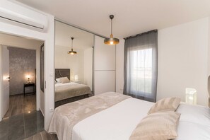 Ein modernes Schlafzimmer mit einem großen Bett, einem Einzelbett, einem begehbaren Kleiderschrank und einem Badezimmer.