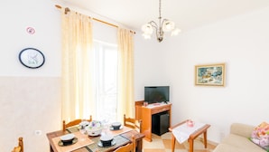 Una sala de estar acogedora con comedor, televisor y un cuadro en la pared.