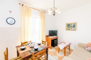 Ein gemütliches Wohnzimmer mit Essbereich, einem Fernseher und einem Bild an der Wand.