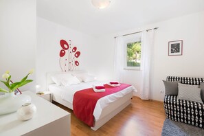Ein Hotelzimmer mit einem Bett, einem Sessel, einem Fenster und einem Wandbild.