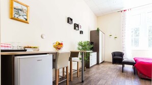 A compact living space with a kitchenette, a dining area, and a seating area with a red bedspread. - Charming and Historic Old Town Apartments - Double Room (Zadar)