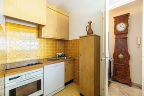 Une cuisine compacte avec des meubles en bois, un four encastré et un lave-vaisselle.
