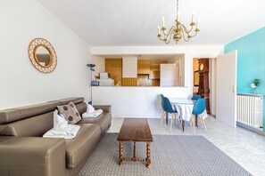 Ein modernes Wohnzimmer mit Sofa, Couchtisch und Essbereich mit Stühlen.