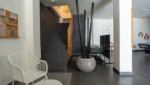 Ein modernes Interieur mit einer Treppe, einem Empfangsbereich und einer Sitzecke mit Stühlen.