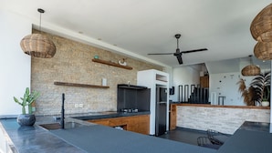 Eine moderne Küche mit Steinwand, schwarzen Arbeitsflächen und einem eingebauten Kühlschrank.
