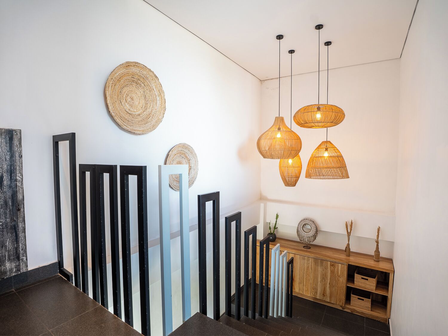 Een modern interieur met een houten console, wanddecoratie van geweven materiaal en hanglampen.