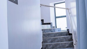 A staircase with a handrail, leading to a landing with a window. - Ink & S Apartment Hotel (Kigali)