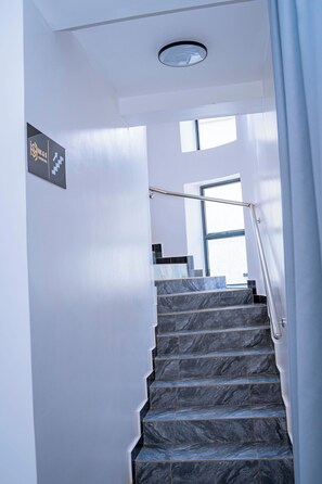 Una escalera con barandilla que lleva a un rellano con ventana.