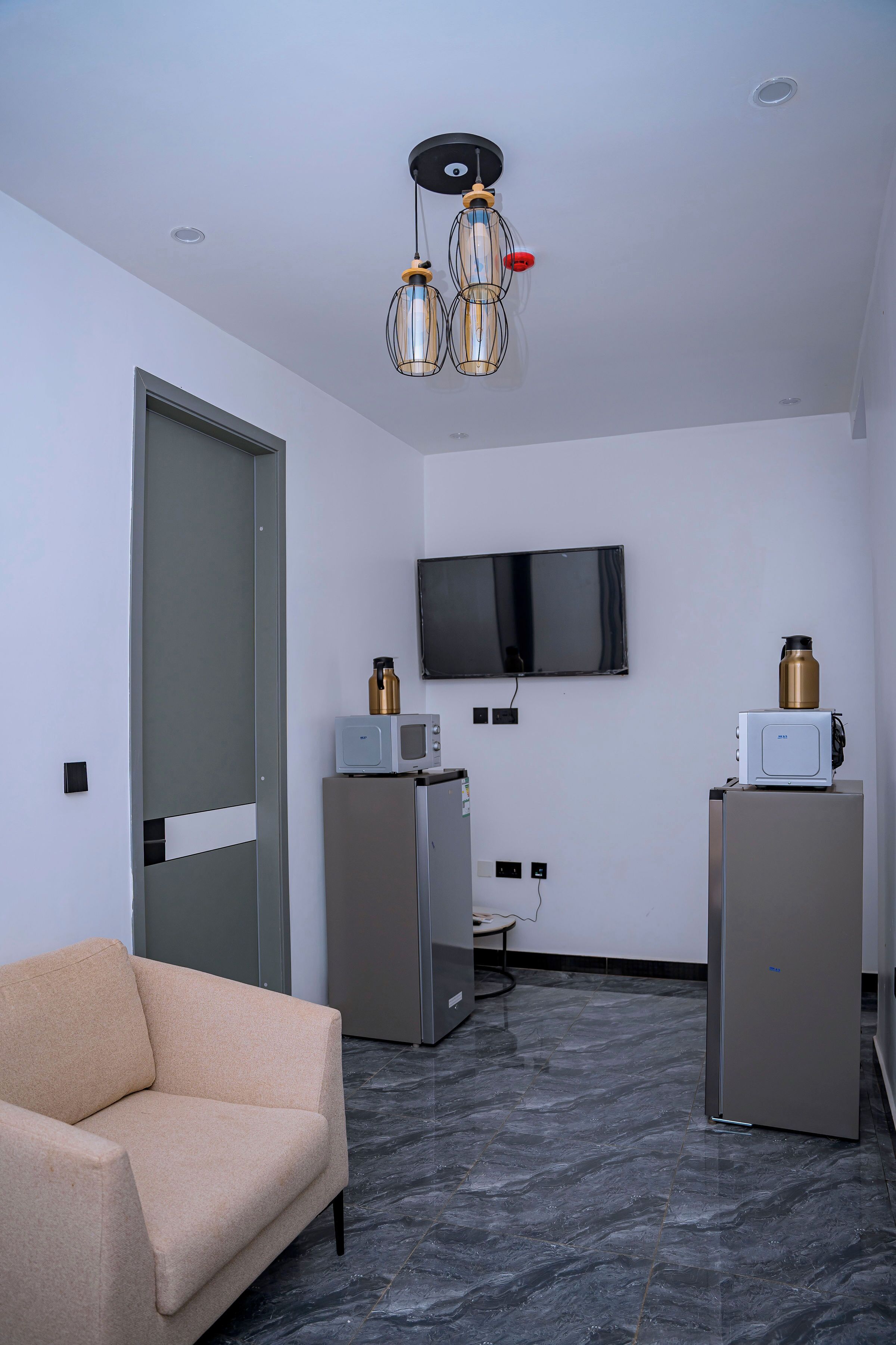 Quarto moderno com sofá, televisão de tela plana na parede e dois refrigeradores.