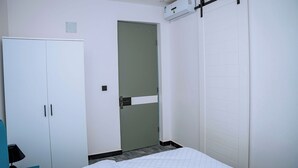 Una habitación de hotel con cama, armario, puerta y unidad de aire acondicionado.