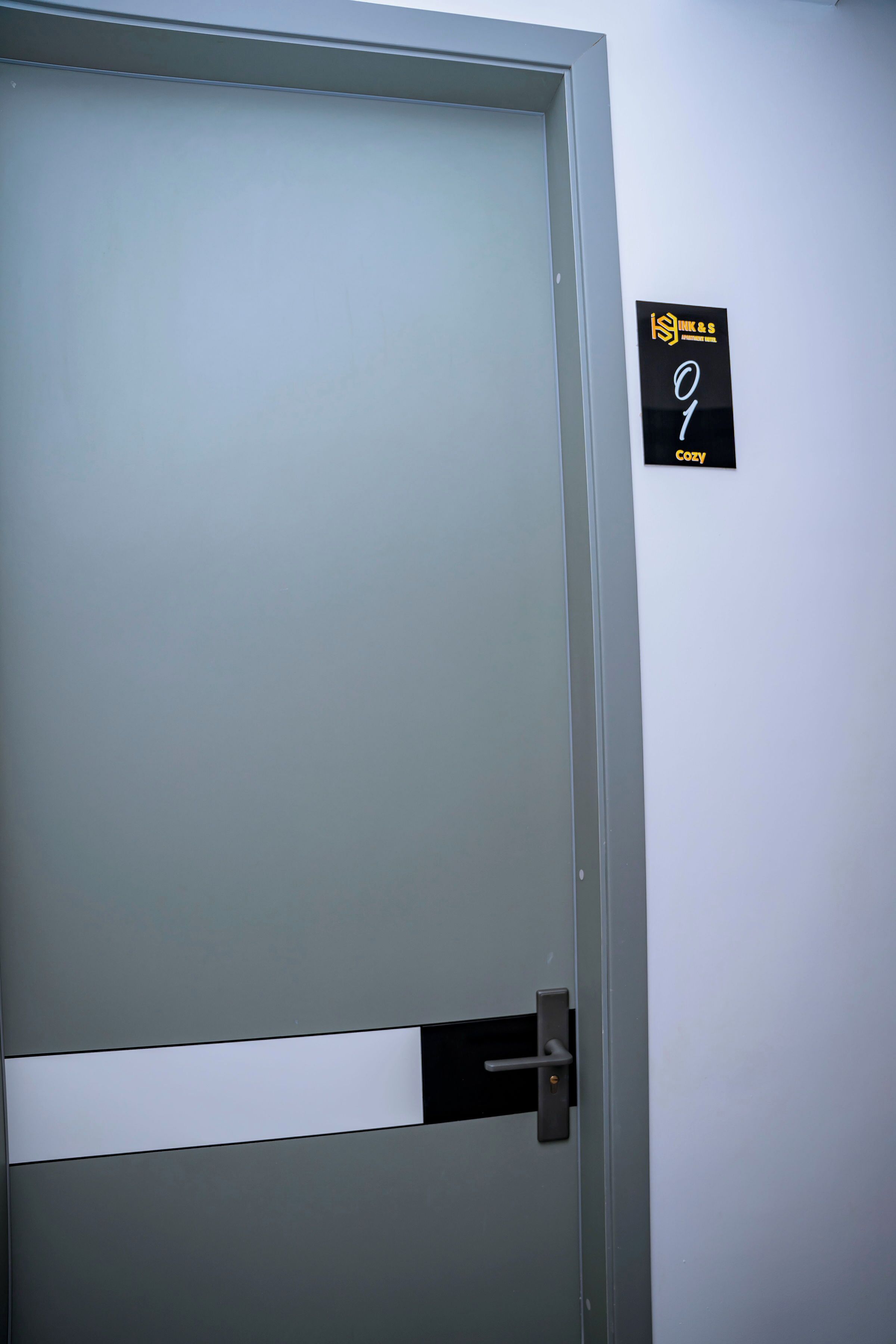 A door with a frosted glass panel and a black sign with yellow text on the wall.