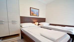 Une chambre d’hôtel avec deux lits simples, une armoire et un tableau au mur.