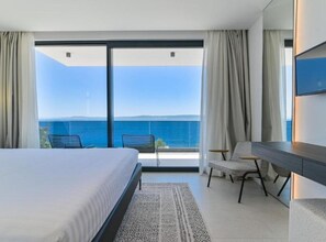 Ein Hotelzimmer mit Bett, Schreibtisch, Stuhl und Meerblick.