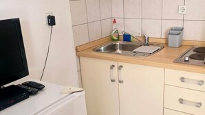 Eine Küche mit Spüle, Arbeitsplatte und Schränken. Auf einem Tisch befinden sich ein Fernseher und Fernbedienungen.