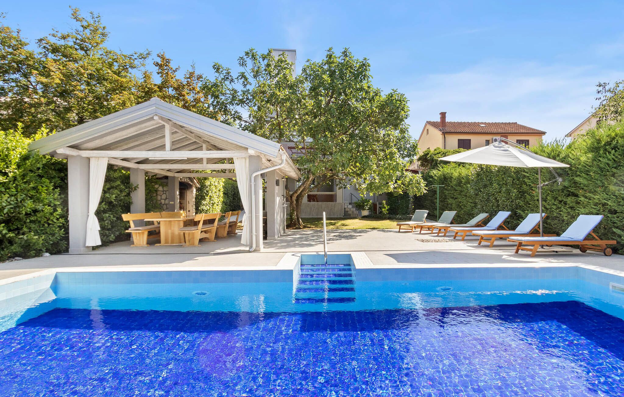 Piscina com espreguiçadeiras e área de estar coberta.