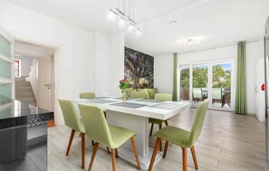 A modern dining area with a white table, green chairs, and a vase with flowers. - Nice home in Jadranovo (Jadranovo)