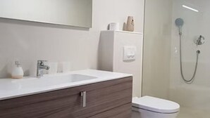 A modern bathroom with a white vanity, a mirror, a toilet, and a shower area. - Residence Maša- Standard Double Room S8 (Budva)