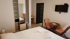 Hotellihuone, jossa on sänky, työpöytä, tuoli, televisio ja vaatekaappi.