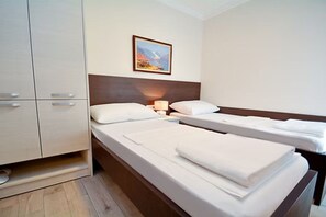 Ett hotellrum med två separata sängar, en garderob och en tavla på väggen.