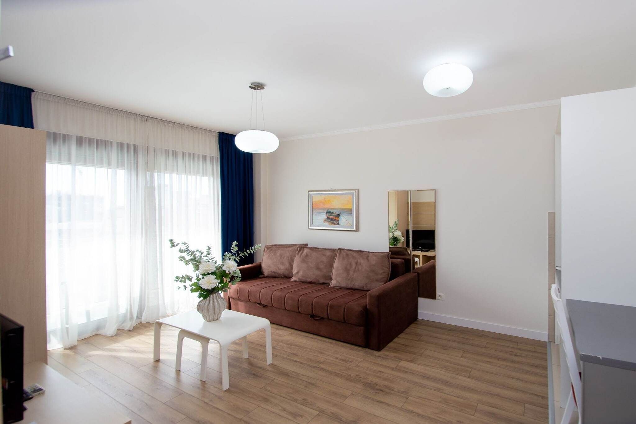 A living room with a brown sofa, a white table, and a painting on the wall.