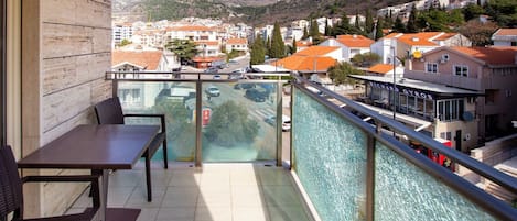 Uma varanda com vista para uma cidade e montanhas, uma mesa e cadeiras.