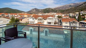Un balcón con vistas a un pueblo costero, que muestra casas escalonadas y montañas al fondo.