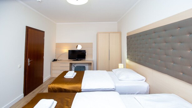 Habitación de hotel con dos camas, un escritorio con computadora, armario y televisor.