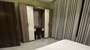 Un dormitorio con una cama grande, un escritorio con silla, un armario y un espejo.