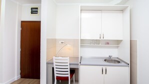 A compact kitchen with a sink, cabinets, and a chair. - Hotel Princ- Standard Twin Room 305 (Budva)