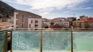 A balcony with a view of a coastal town, including buildings and a construction site. - Hotel Princ- Standard Twin Room 305 (Budva)