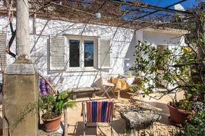 Eine Terrasse mit Tisch, Stühlen und Topfpflanzen.